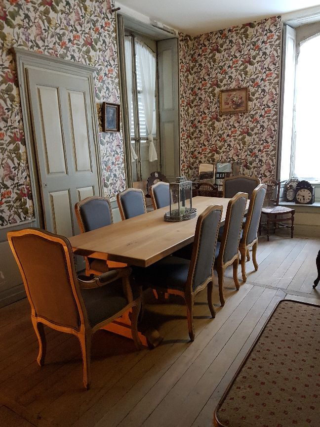 De eetkamer met lange tafel en gebloemd behang